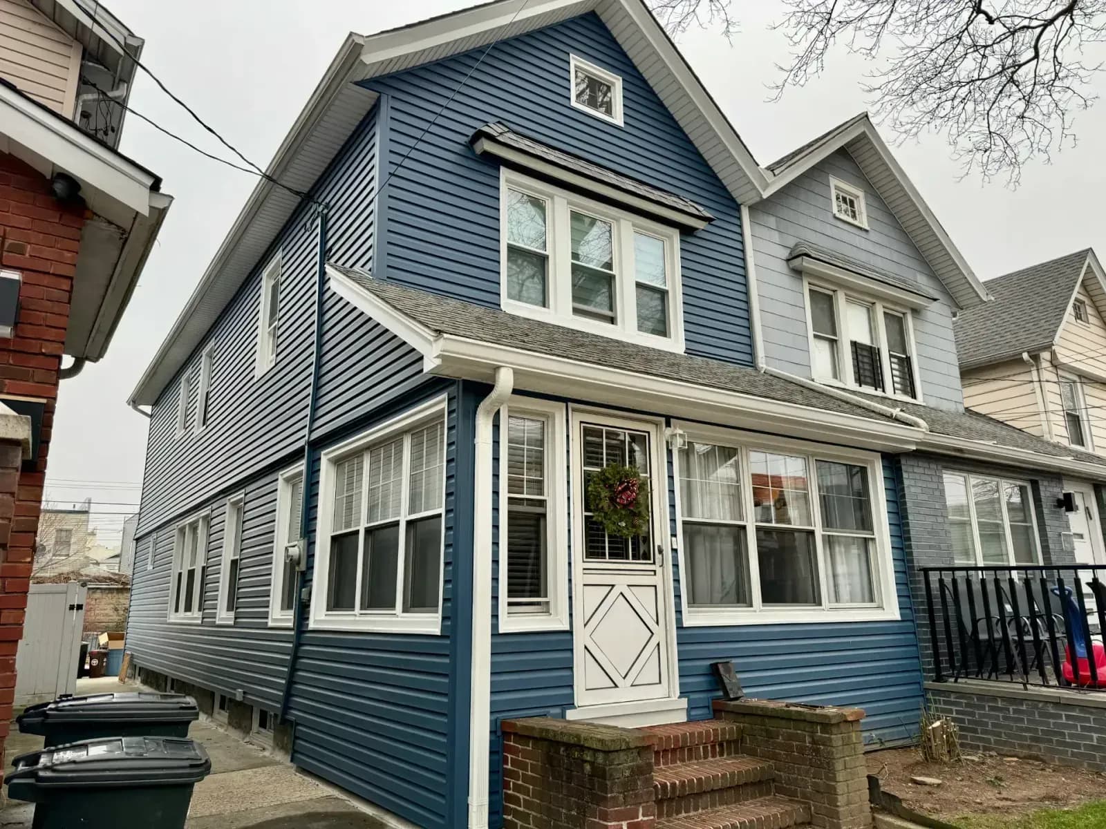 Two-story house with dark blue horizontal siding, white trim, and a matching enclosed front porch.
