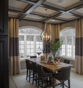A dining room with a chandelier, large table, and beige and brown drapes